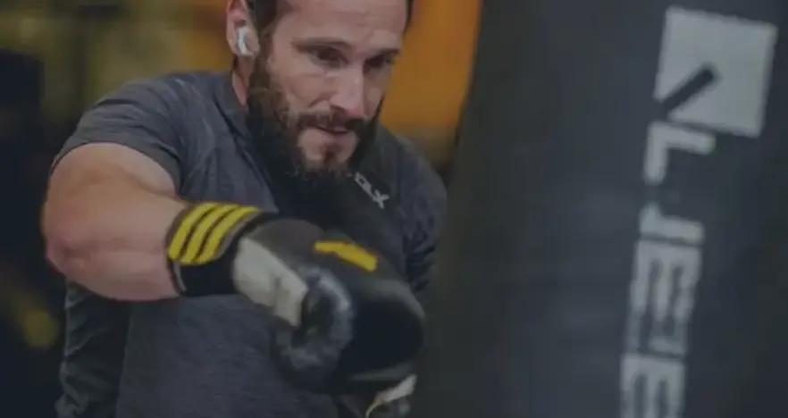 Man in black t-shirt punching a boxing bag