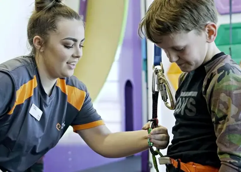 Instructor setting up child for clip n climb