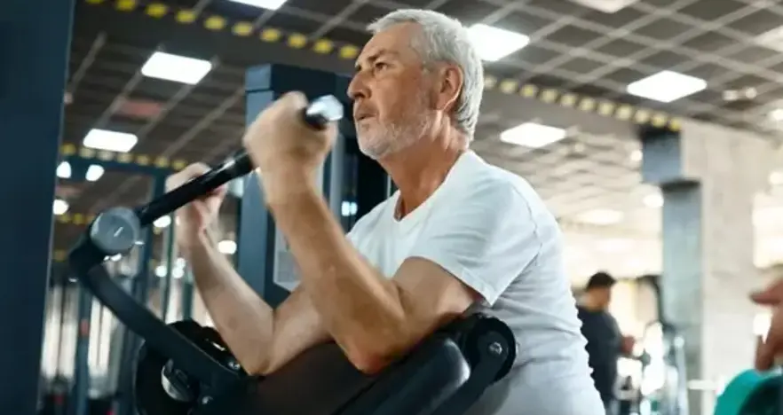 Senior gym goer using weights machine