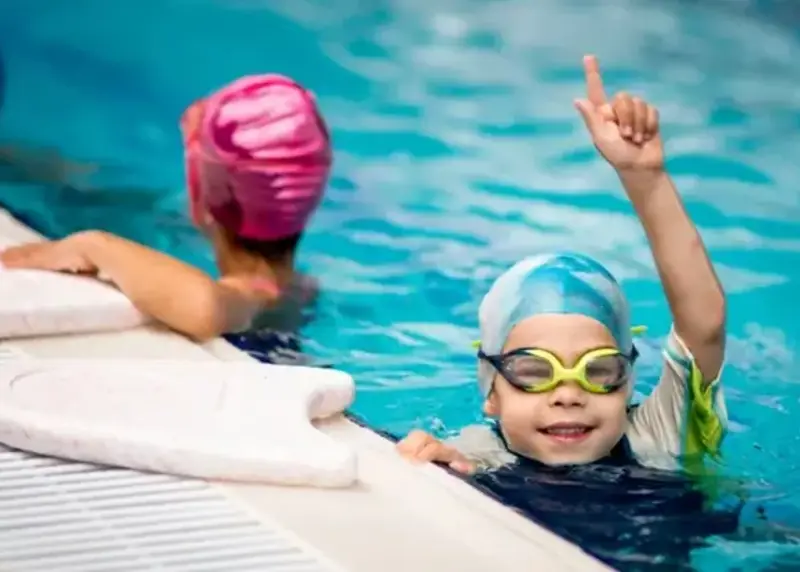 Child in a swim cap smiling in pool